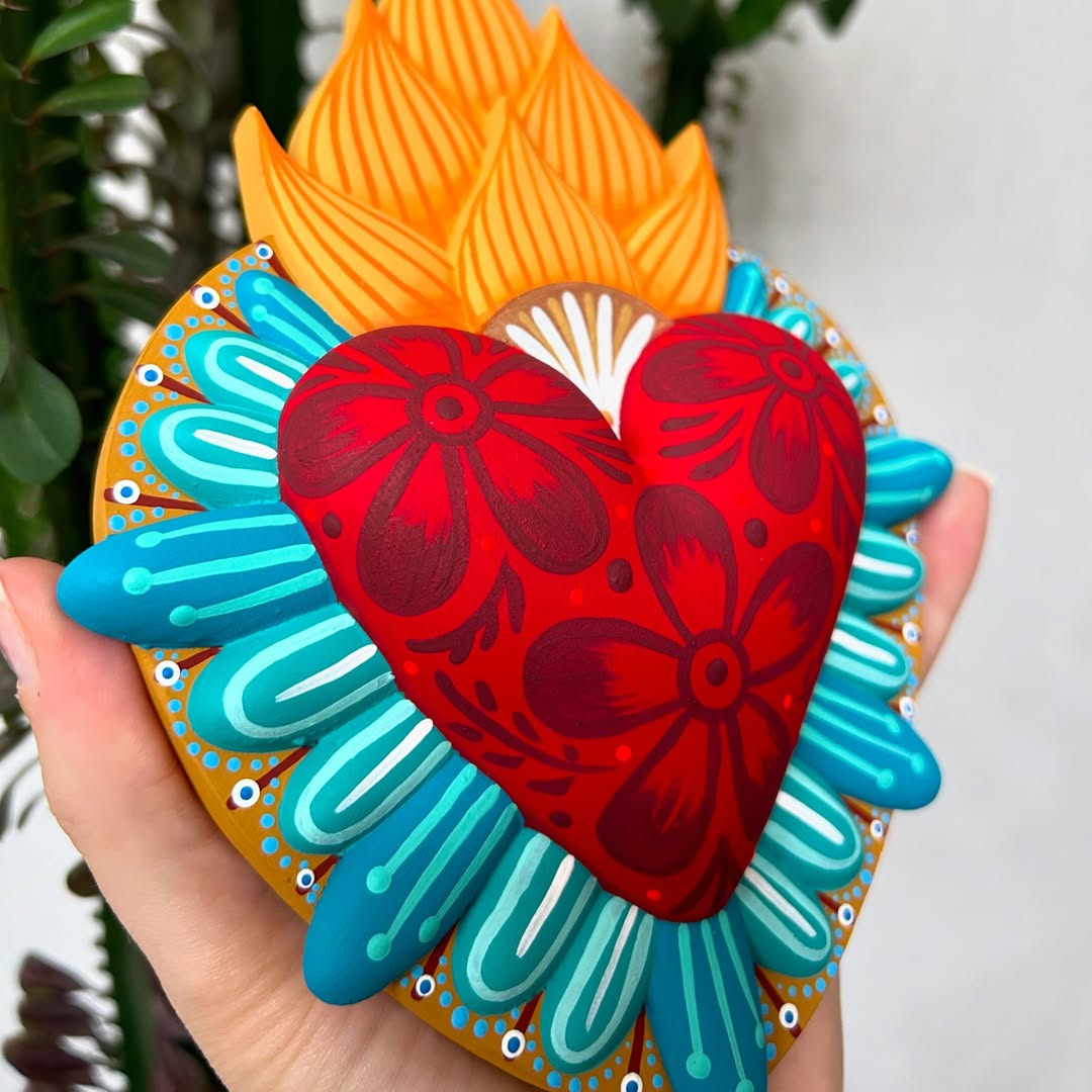 Hand-painted Mexican fire heart folk art sculpture with floral red heart, vibrant orange flames, and turquoise border, symbolizing love, passion, and spiritual devotion