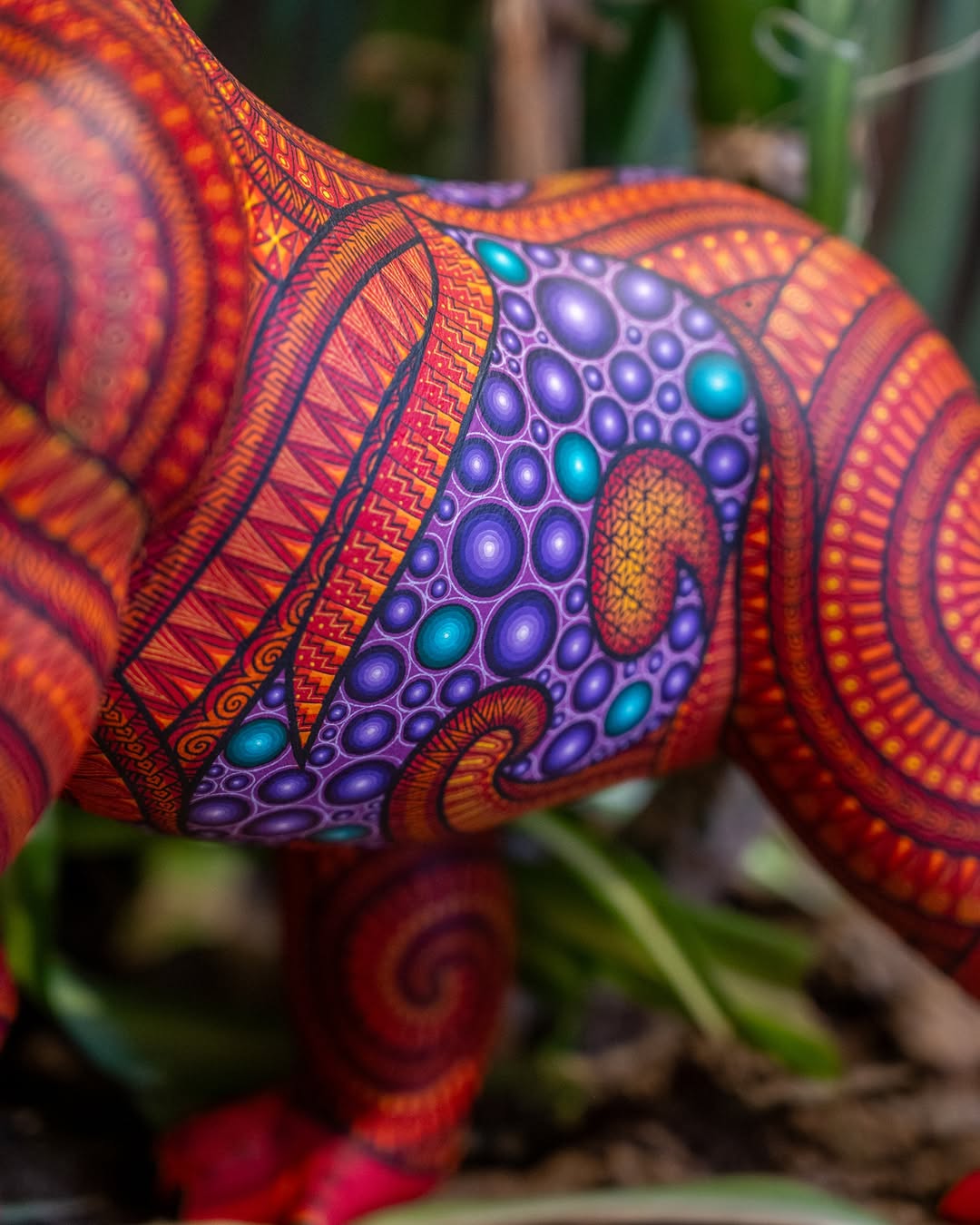 Hand-painted gorilla alebrije with vibrant patterns and intricate Mexican folk art details, displayed with tropical plants in the background