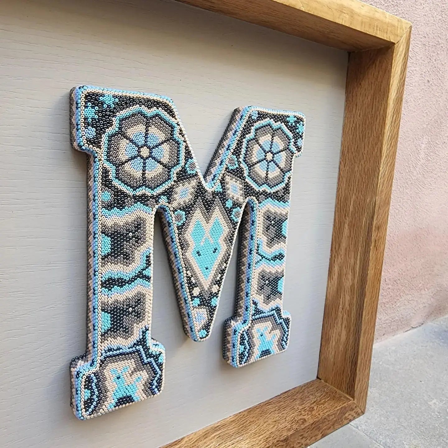 letter decorated with beads in the style of huichol art, mexican crafts