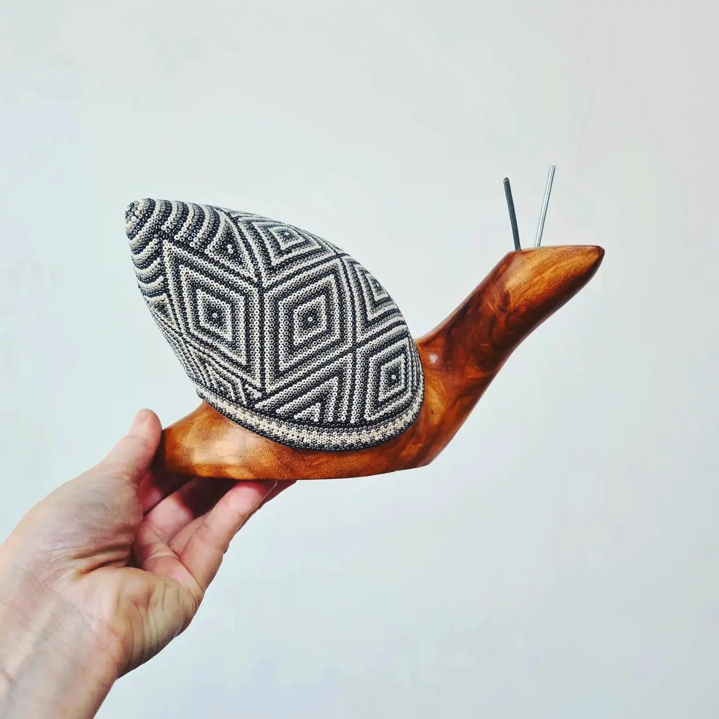 wooden snail sculpture decorated with beads in the huichol style, mexican crafts