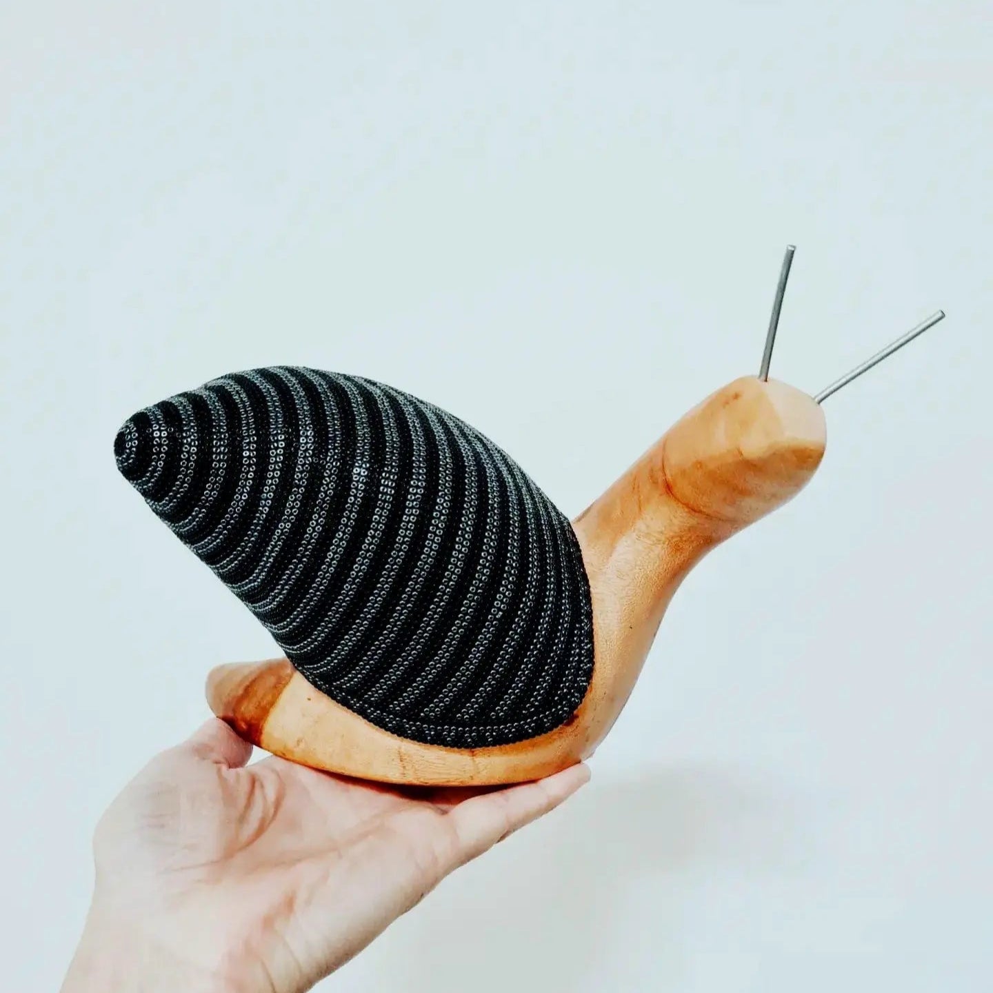 wooden snail sculpture decorated with beads in the huichol style, mexican crafts