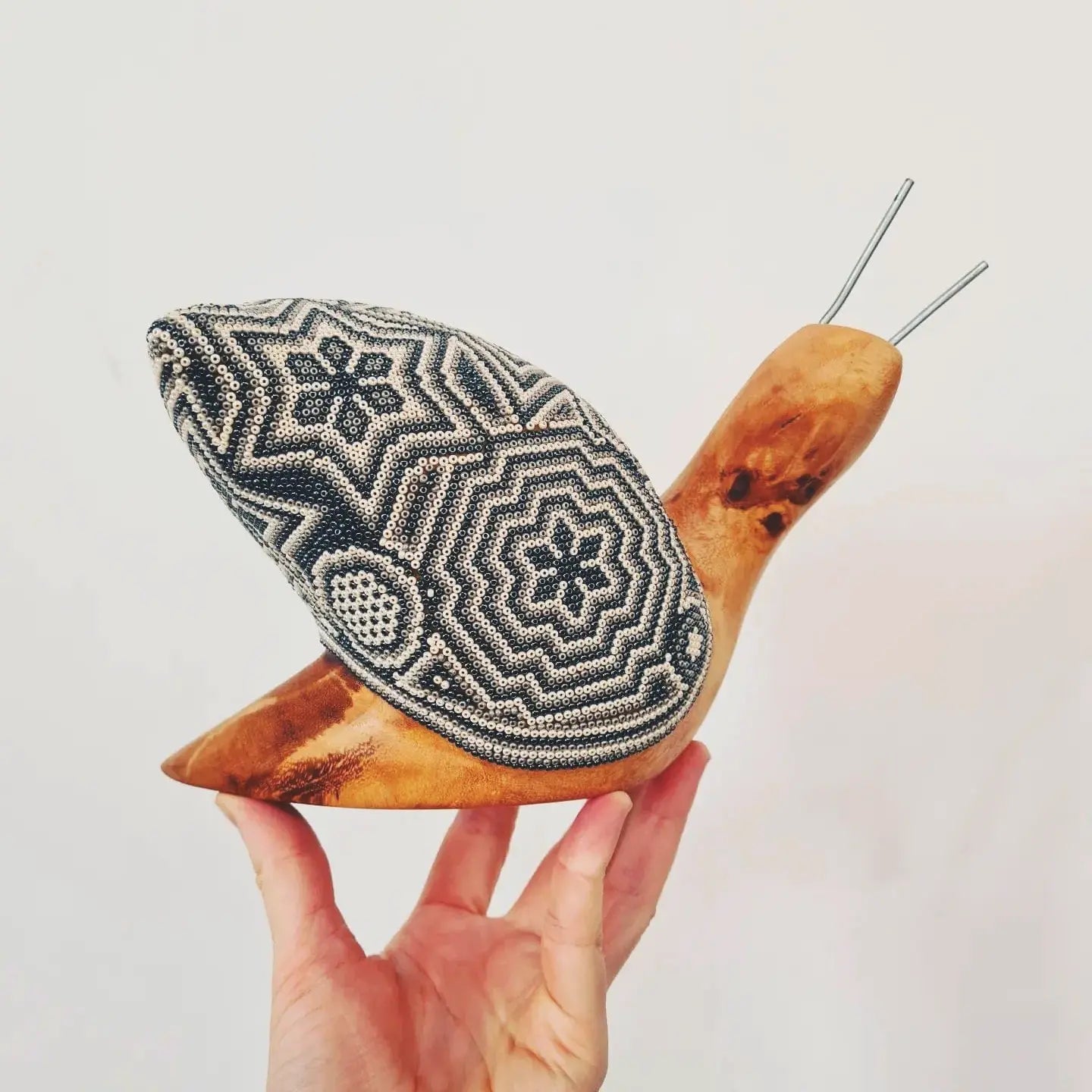 wooden snail sculpture decorated with beads in the huichol style, mexican crafts